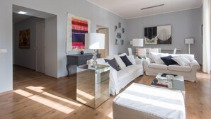 A modern living room with a glass coffee table, white sofas, and a large mirror. - La Casa dell'Arte by Interhome (Rome: Historical City Center)