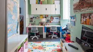 Habitación infantil con escritorio, sillas, estantería y un mapa del mundo.