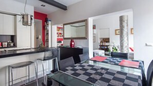 Una cocina moderna con armarios blancos, encimera negra y un colgador para ollas.