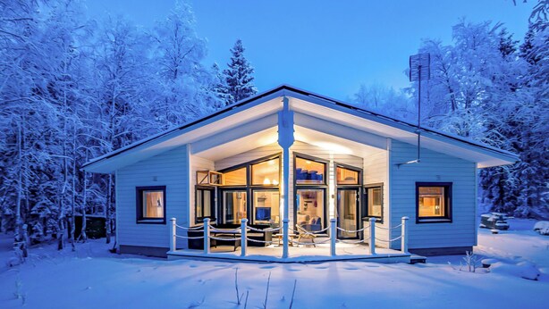 A snow-covered house with a porch and large windows.