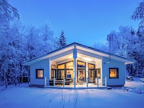 Ein mit Schnee bedecktes Haus mit Veranda und großen Fenstern.