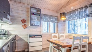 A modern kitchen with wooden cabinets, a built-in oven, and a dining area with white chairs and a wooden table.