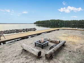 Terraza junto al lago con una fogata y zona de estar.
