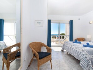 Habitación de hotel con balcón, mobiliario de mimbre y ropa de cama estampada.