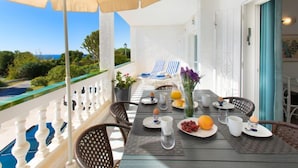 En balkon med et morgenmåltid ved et bord, med udsigt til en pool og grønne områder.