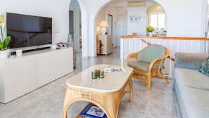 En moderne stue med et fladskærms-tv, et flet kaffebord, en sofa og et spiseområde med en bar.
