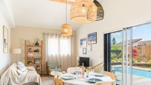 Un salon confortable avec un coin repas, un canapé, une télévision et une vue sur une piscine.