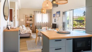 Une cuisine moderne dotée d’un grand îlot central, d’appareils électroménagers intégrés et offrant une vue sur un jardin.