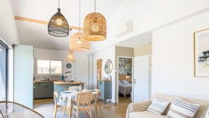 Un salon moderne avec un canapé, une table à manger et des chaises, et une cuisine en arrière-plan.