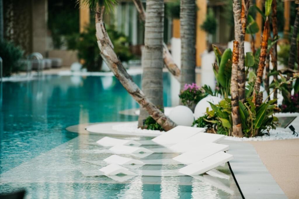 A pool area with lounge chairs and palm trees.