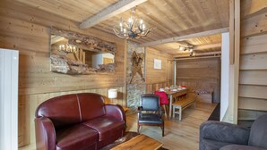 A cozy cabin interior with a wooden ceiling, a red leather sofa, a wooden coffee table, and a dining area with a table and chairs. - Bright duplex for 8 people, near center, Méribel (Méribel)