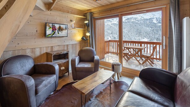 A cozy cabin interior with a fireplace, leather sofas, a wooden table, and a large window overlooking a snowy landscape. - Bright duplex for 8 people, near center, Méribel (Méribel)