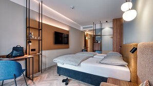 A modern hotel room with a bed, a desk, a chair, and a wardrobe. - Stadthotel Neumarkt Mitte (Neumarkt in der Oberpfalz)