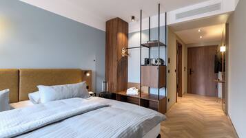A modern hotel room with a large bed, wooden headboard, and a built-in wardrobe with shelves.