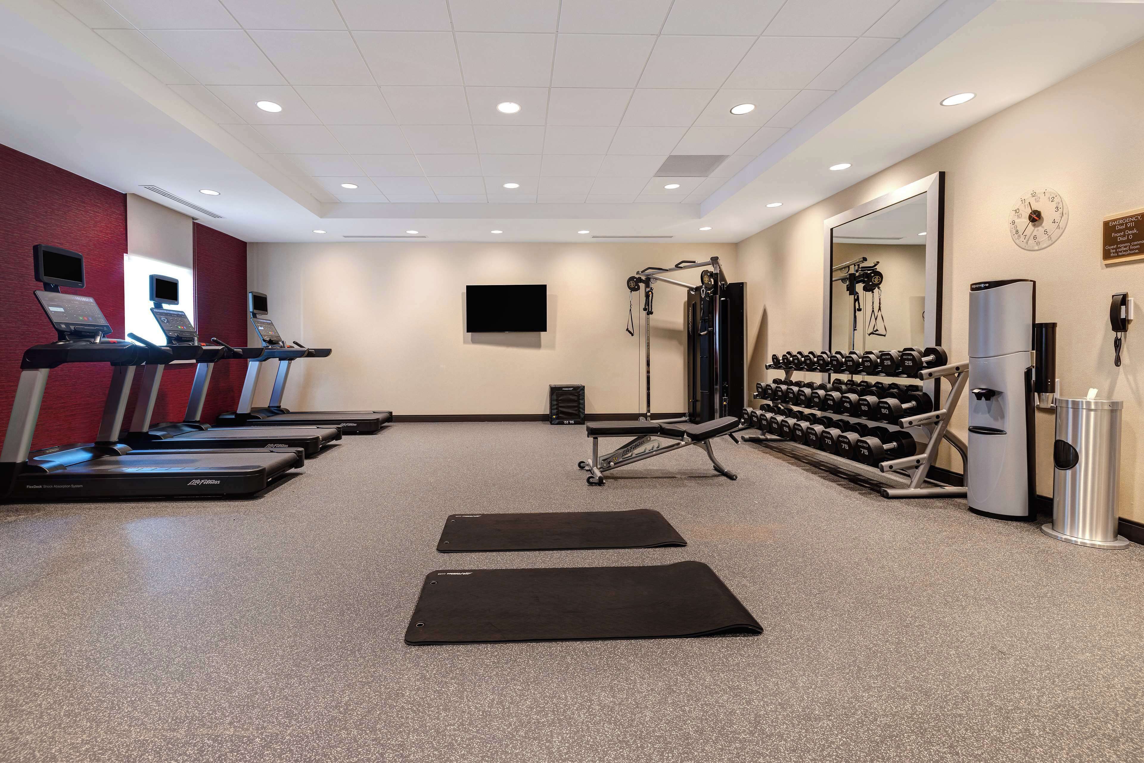 A gym with treadmills, weights, and exercise mats.