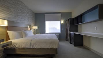 A modern hotel room with a large bed, bedside tables, a desk, and a window with a city view.