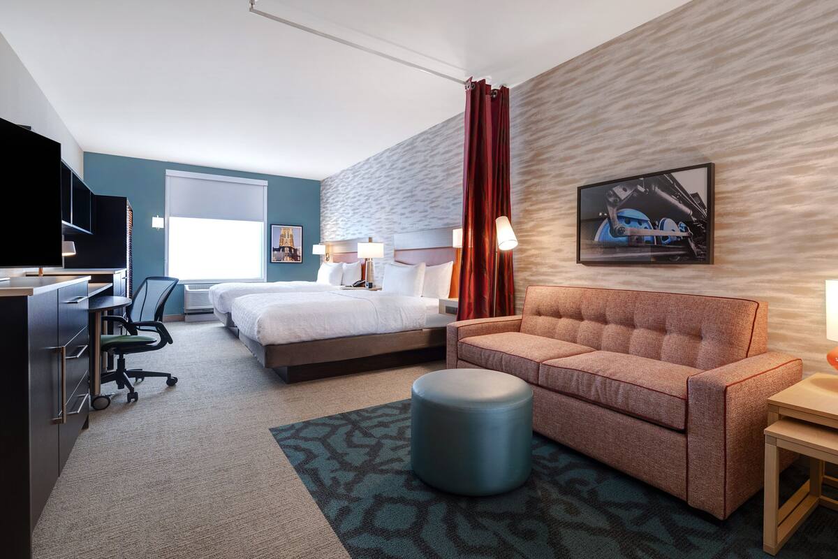 Une chambre d’hôtel avec un lit, un canapé, un bureau et une télévision.