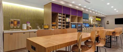 A modern restaurant with wooden furniture, a counter with beverages, and a seating area with tables and chairs.