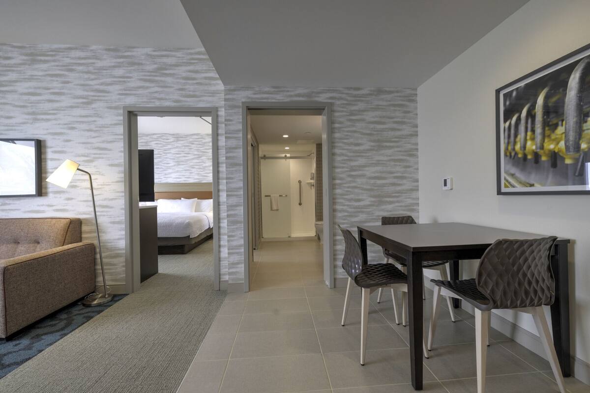 Une chambre d’hôtel avec un lit, un bureau avec des chaises, une télévision et un tableau au mur.