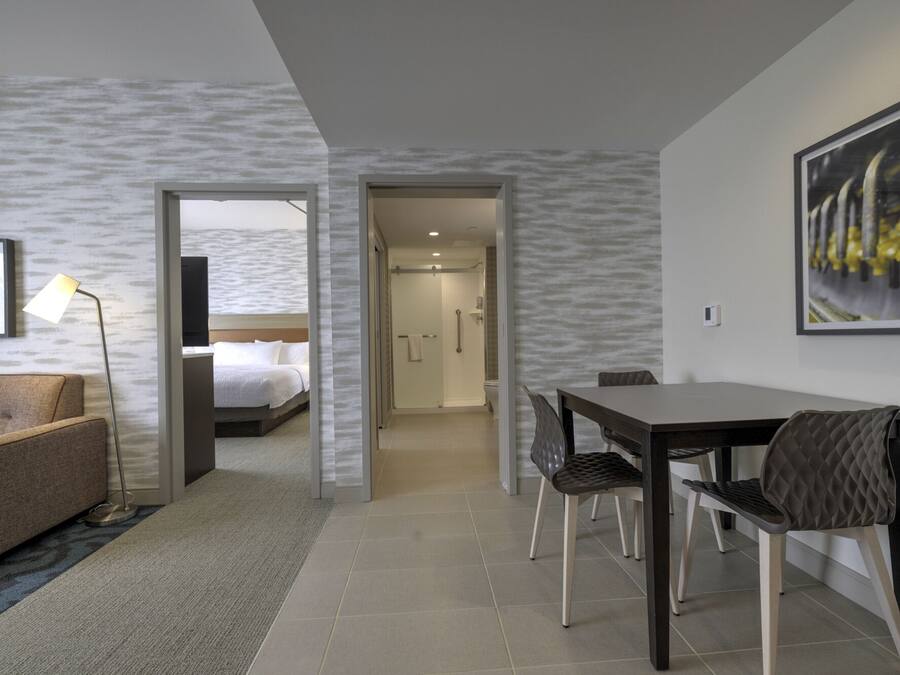Una habitación de hotel con una cama, un escritorio con sillas, un televisor y un cuadro en la pared.
