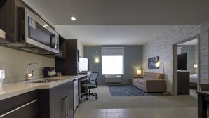 Ein modernes Hotelzimmer mit Küchenzeile, einer Couch, einem Fernseher und einer Lampe.