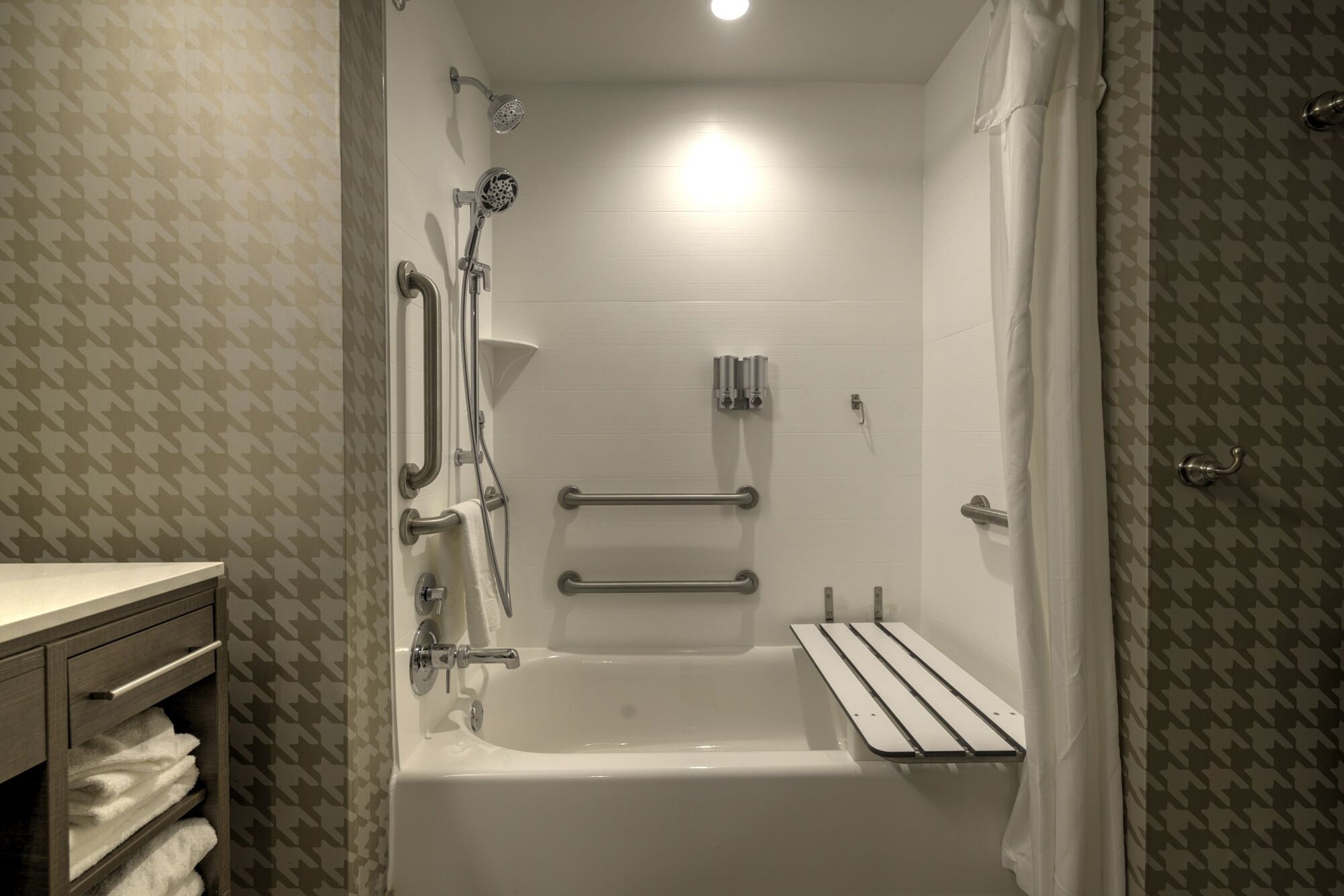 A modern bathroom with a bathtub, shower, and grab bars.