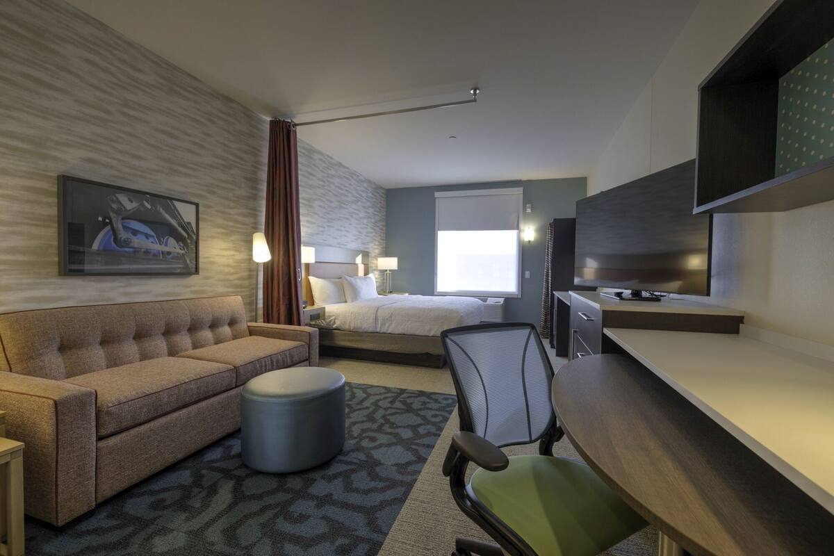 Une chambre d’hôtel comprenant un lit, un canapé, un bureau, une chaise et un téléviseur.