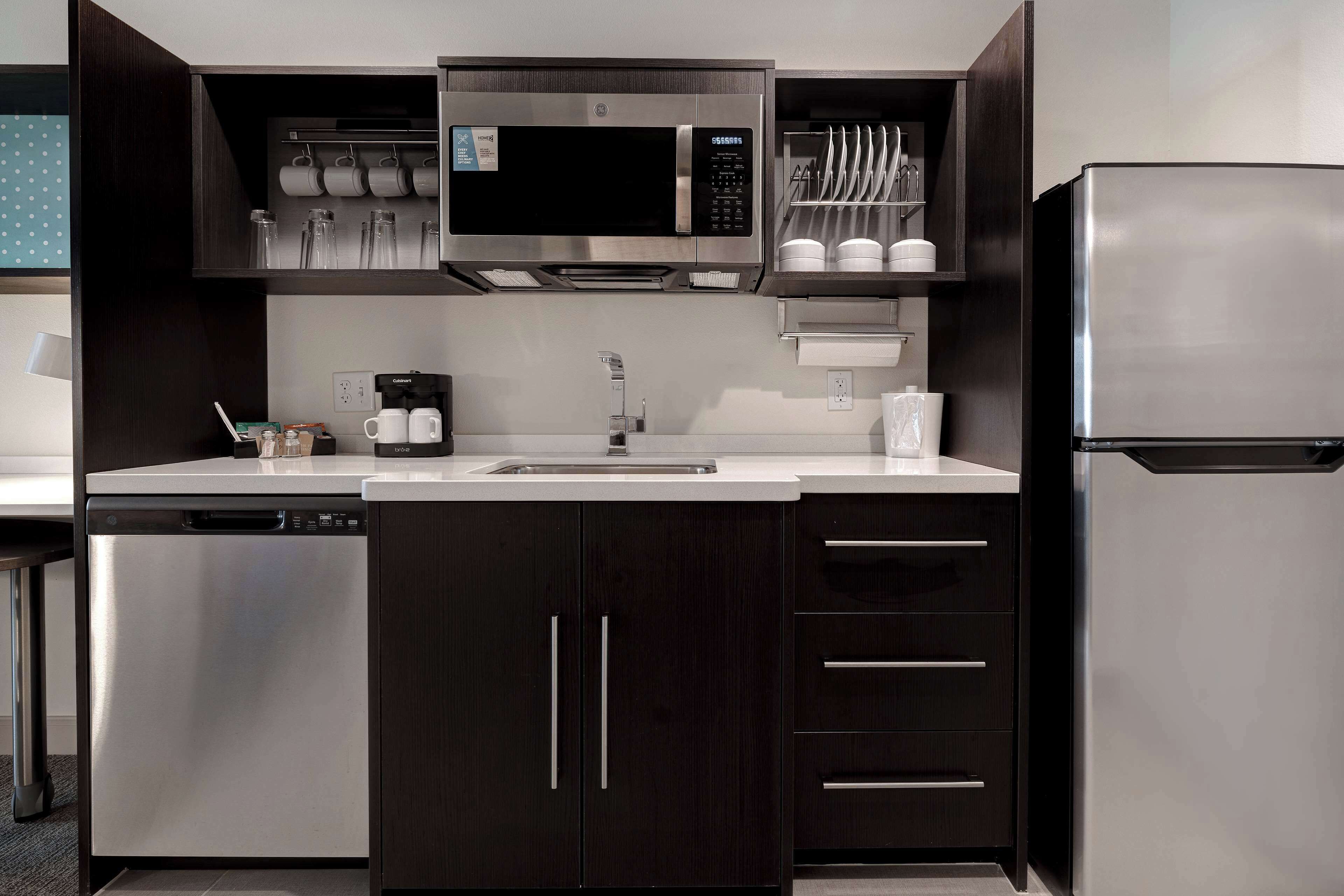 A modern kitchen with a built-in microwave, stainless steel refrigerator, and a dishwasher.