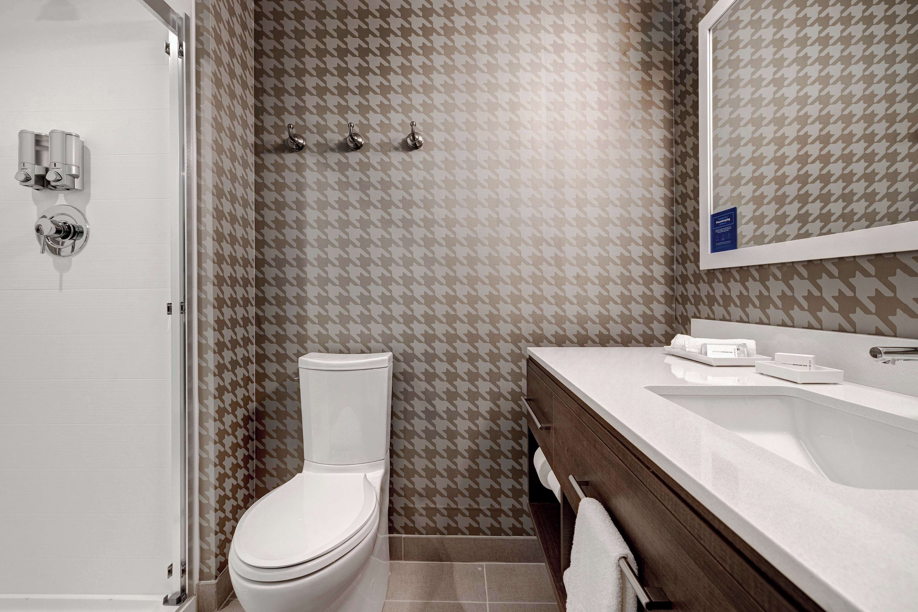 A modern bathroom with a white toilet, a shower with a glass door, and a vanity with a mirror.