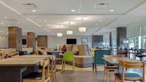 Eine moderne Hotelhalle mit Sitzgelegenheit, einer Rezeption und großen Fenstern, die für natürliches Licht sorgen.