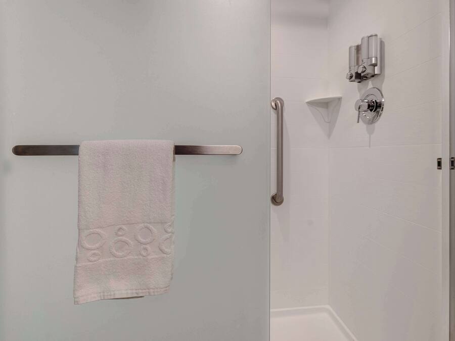 Ein Badezimmer mit Handtuchhalter, Handlauf und Duschkopf.