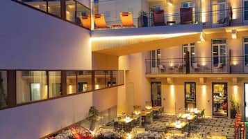 Ein mehrstöckiges Hotel mit Außenbereich, Innenhof und einer gut beleuchteten Fassade.
