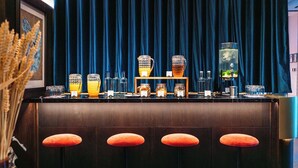 A bar area with a dark blue curtain backdrop, a variety of glassware, and a selection of bottles.