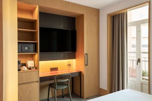 A hotel room with a wooden desk, a flat-screen TV, a minibar, and a view of the outside balcony. - Arts Hotel Porto, Tapestry Collection By Hilton (Porto)