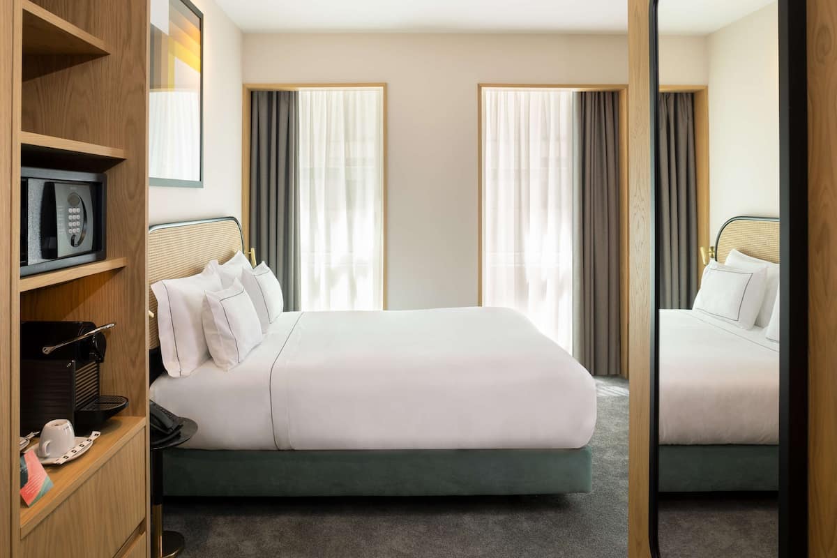 A hotel room with a bed, a wardrobe, a microwave, and a coffee maker.