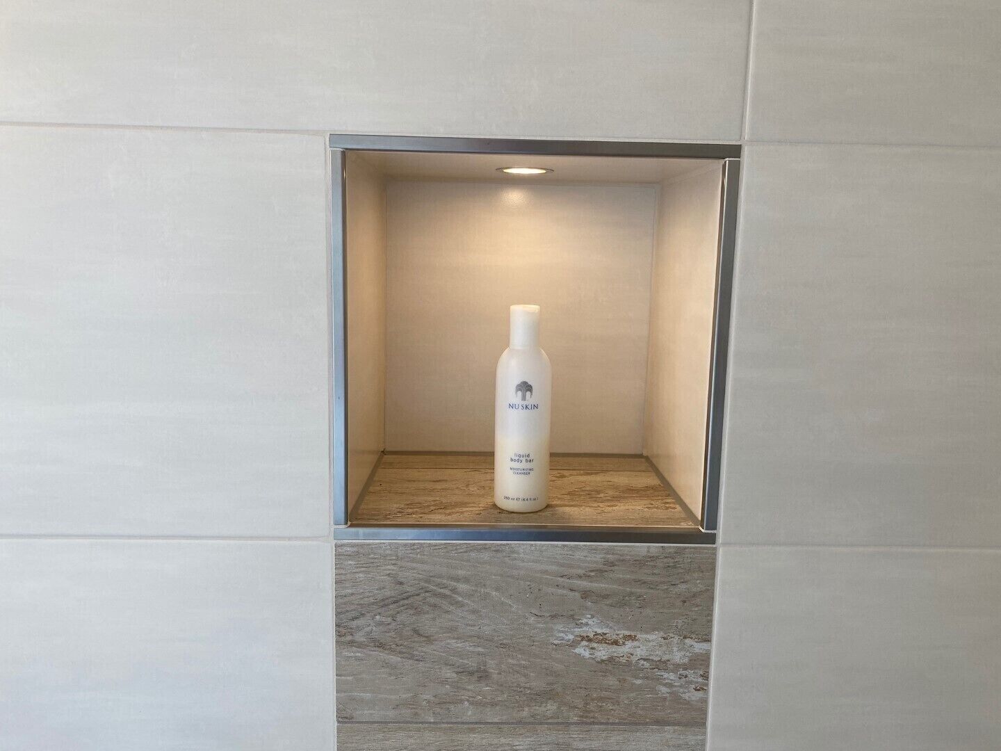 A bottle of NUSKIN moisturizer in a recessed shelf.