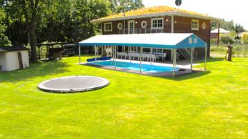 Una casa con piscina, veranda coperta e trampolino.