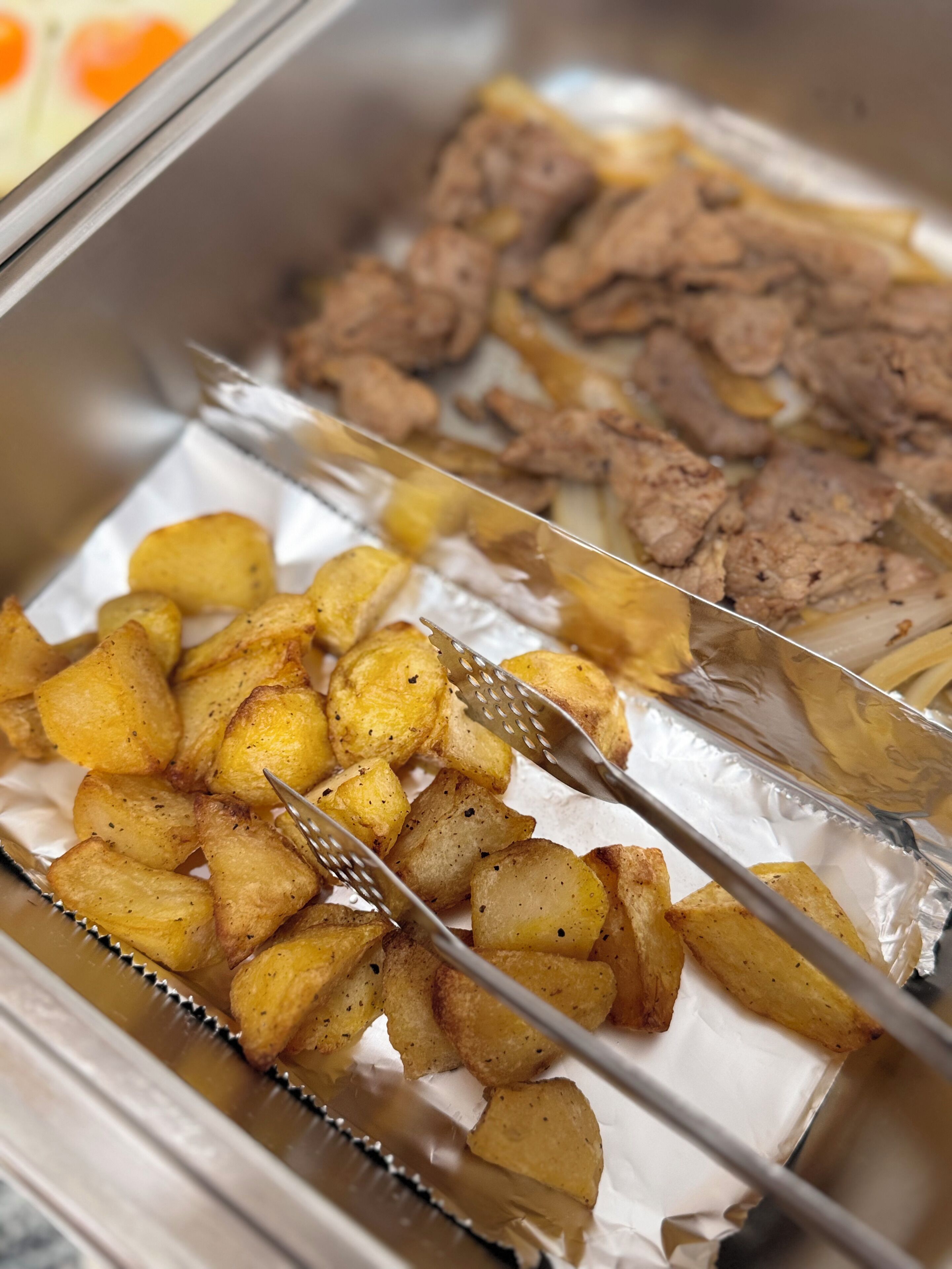 A tray with roasted potatoes and meat.