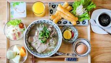 A tray with a bowl of soup, fried items, a glass of orange juice, a bowl of salad, a plate of fried snacks, a cup of tea, and a small bowl of egg.