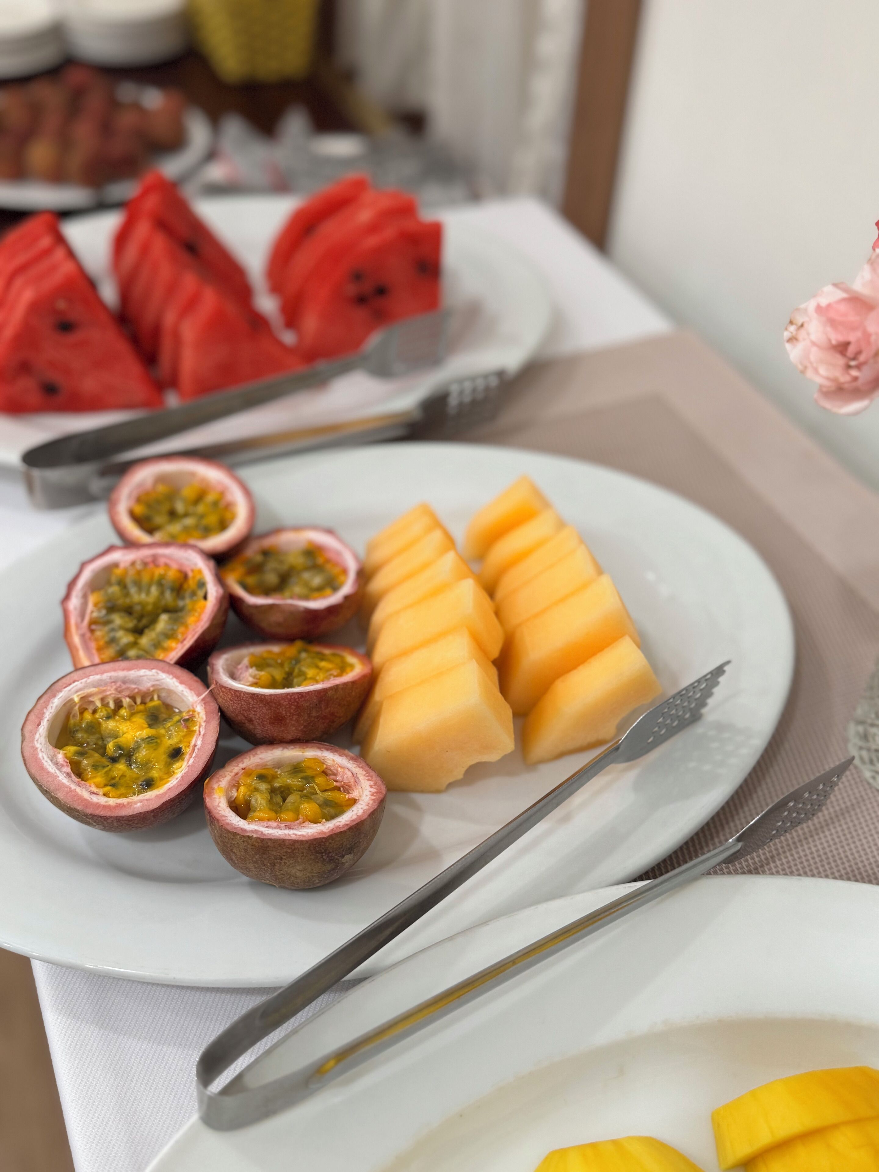 Een bord met gesneden fruit, waaronder passievrucht en mango, met een vork ernaast.