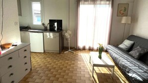 A compact living space with a kitchenette, a sofa, and a dining table.