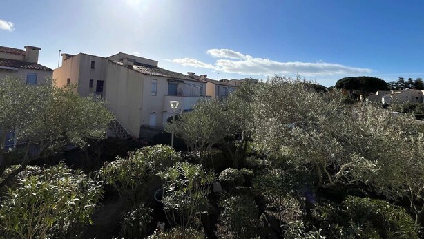 A residential building with a tiled roof, surrounded by dense shrubbery.