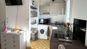 A compact kitchen with a washing machine, microwave, and coffee maker.