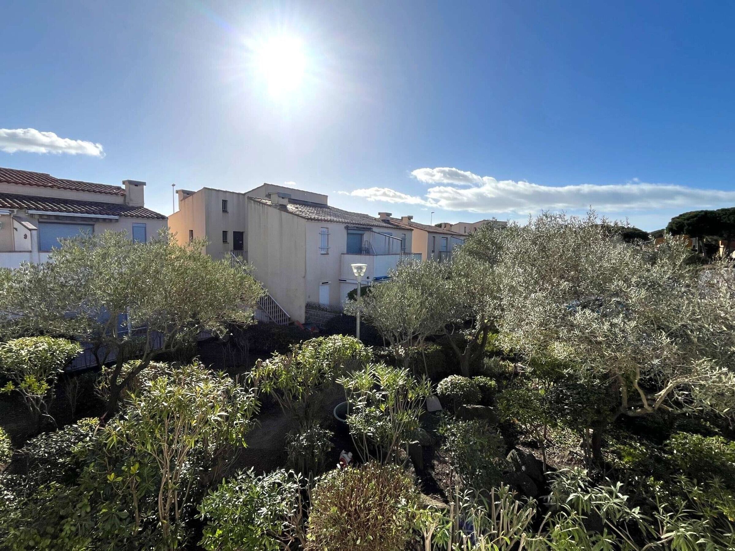Et boligområde med huse, en klar himmel og sollys.