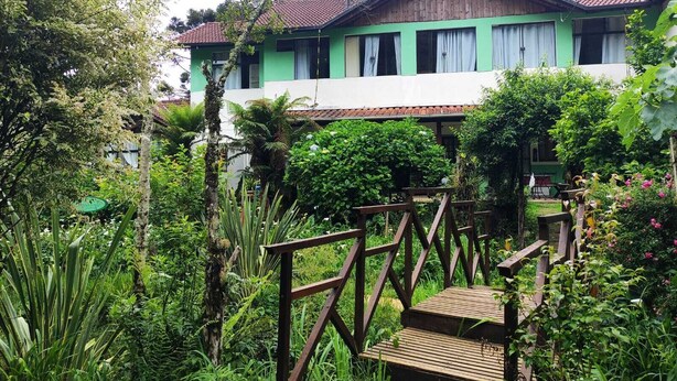 Un edificio de dos plantas con fachada verde y tejado de tejas rojas.