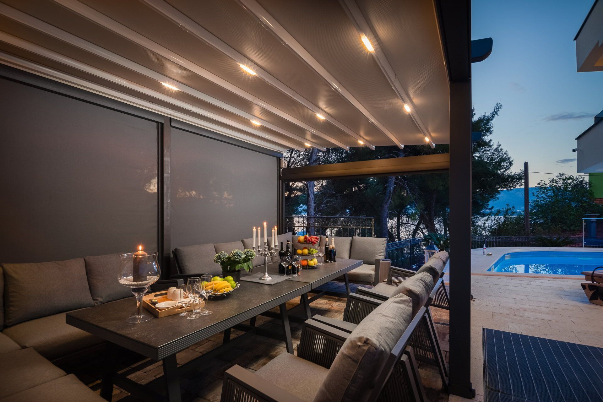 An outdoor dining area with a table set for two, surrounded by cushioned seating.