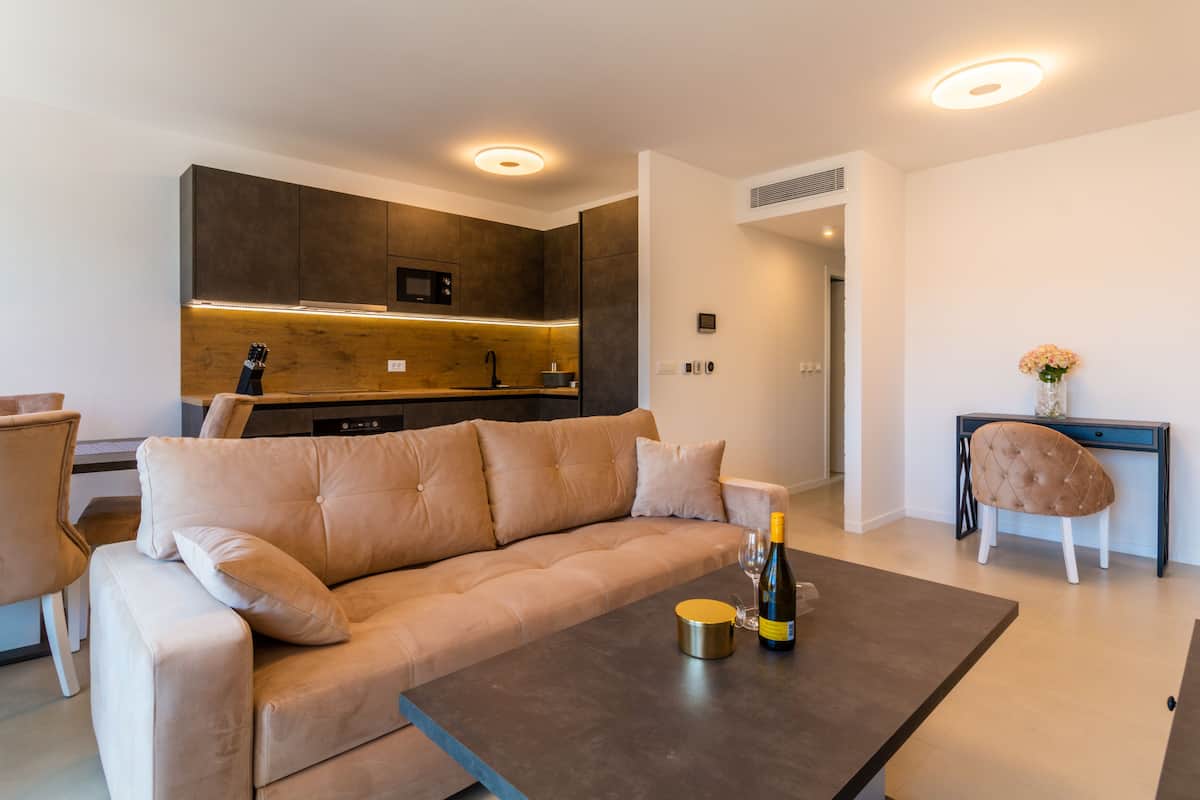 A modern living room with a beige sofa, a coffee table, and a dining area with a dark table.