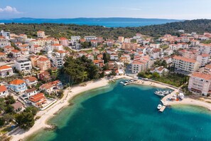 An aerial view of a coastal town with residential buildings, a marina, and a beach. - Beach Villa Valentina (Okrug)