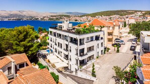 Un edificio moderno con terraza en la azotea, rodeado de edificaciones residenciales y vistas al mar.