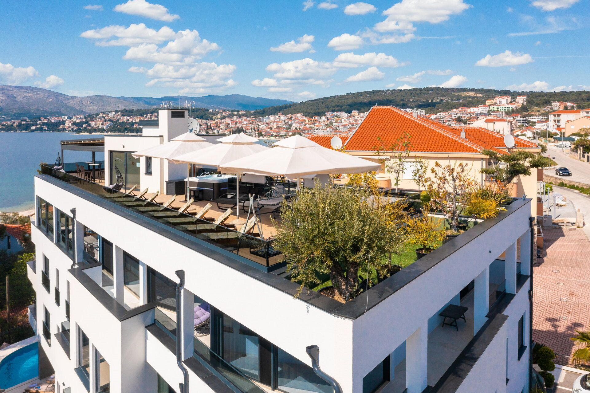 Ein modernes Gebäude mit Dachterrasse, Außenmöbeln und einem Pool.
